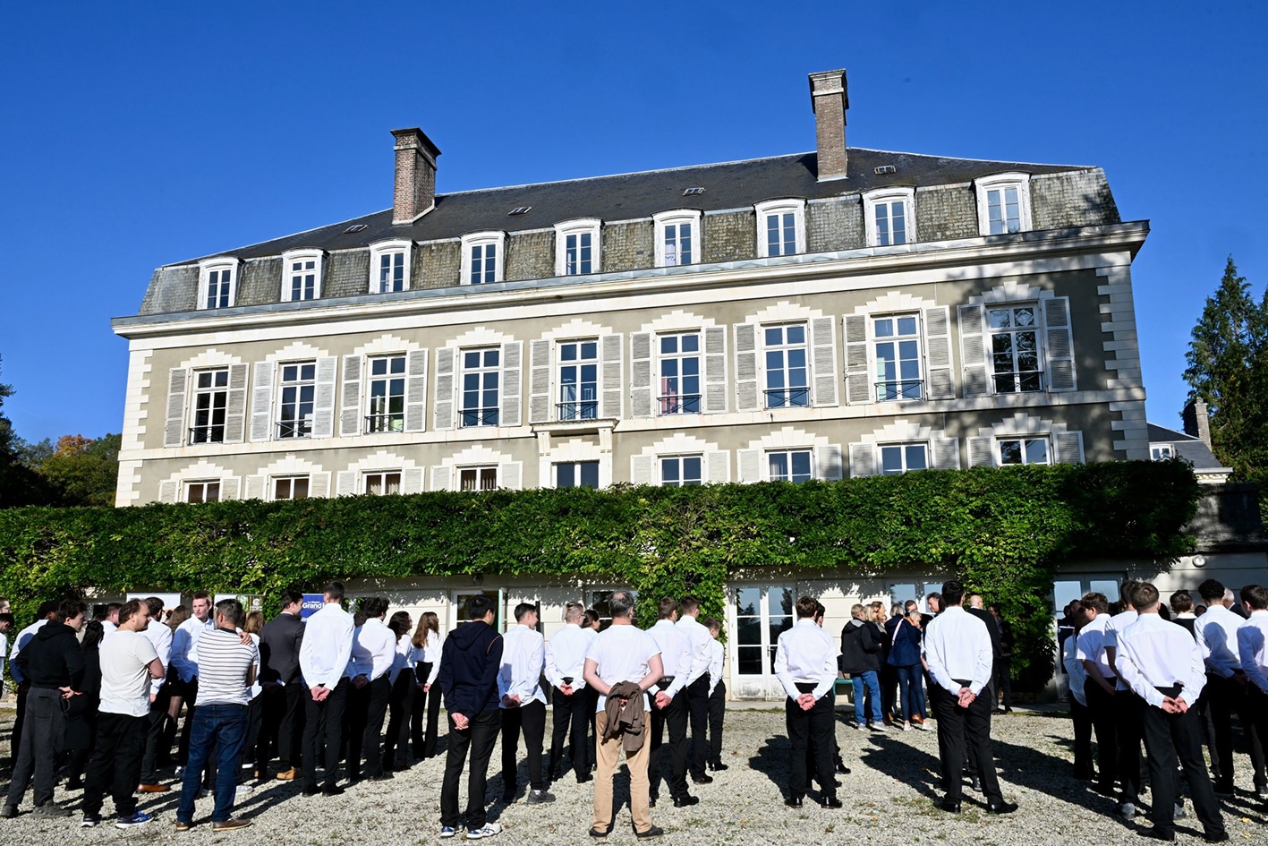 Groupe de personnes devant un grand bâtiment.