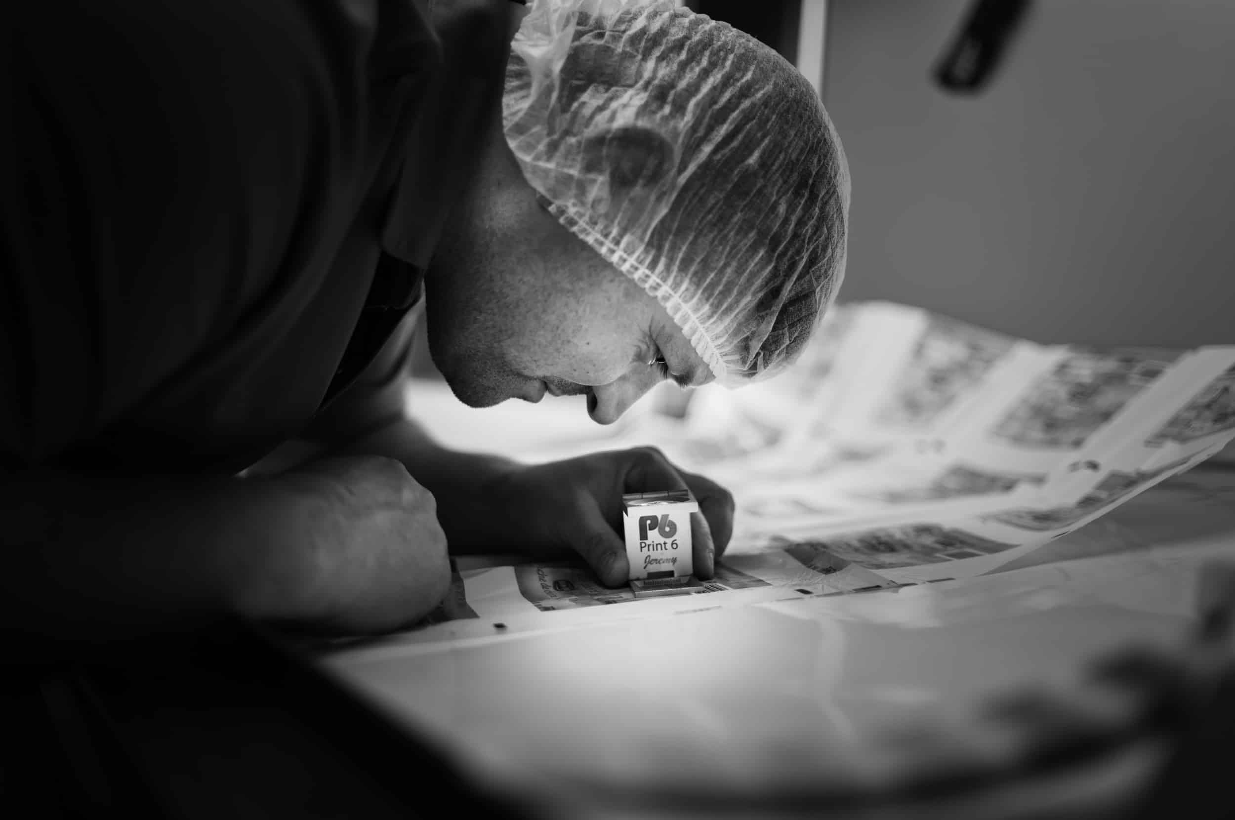 Homme inspectant impression avec outil grossissant.